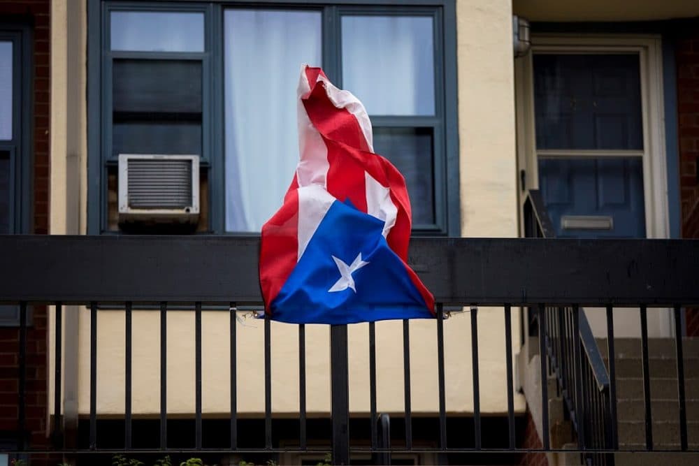 A Puerto Rican flag hanging from the balcony of a West Dedham Street apartment building gets whipped around in the wind gusts of Tropical Storm Jose in September. (Jesse Costa/WBUR)