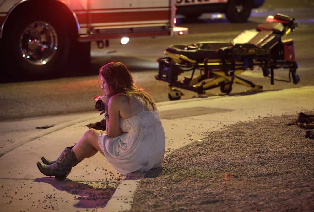 A woman sits on a curb at the scene of the Sunday night shooting along the Las Vegas Strip on Monday morning. (John Locher/AP)