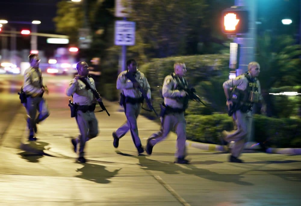 Police run for cover at the scene of a shooting near the Mandalay Bay resort and casino on the Las Vegas Strip on Sunday night. (John Locher/AP)