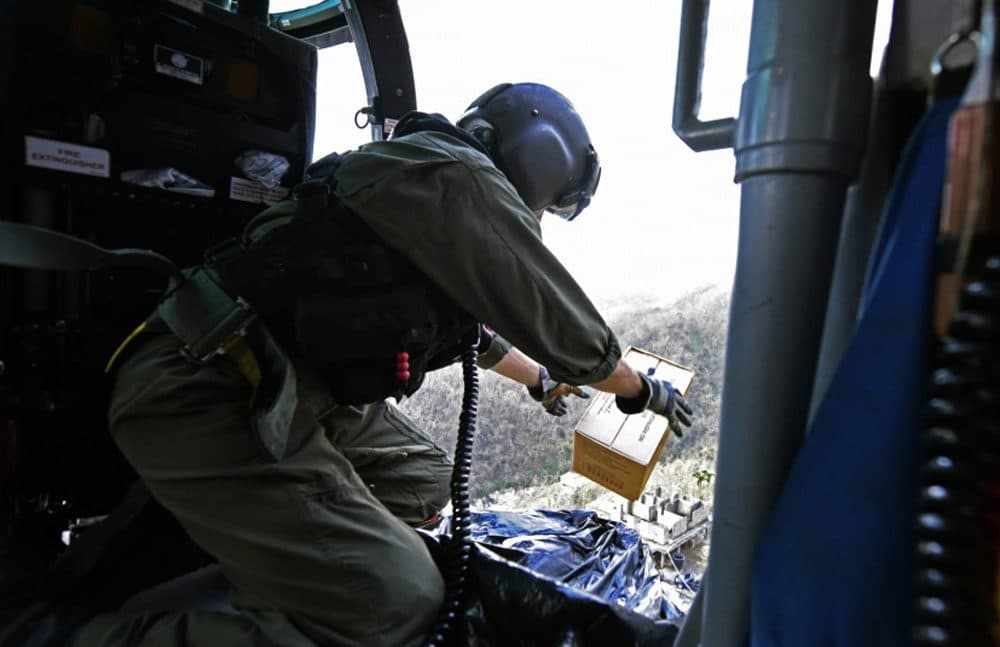 This image made available by the U.S. Coast Guard shows Petty Officer 2nd Class Kenneth Krowel dropping a box of MRE's to stranded residents near Utuado, Puerto Rico on Tuesday. (Eric D. Woodall/U.S. Coast Guard via AP)