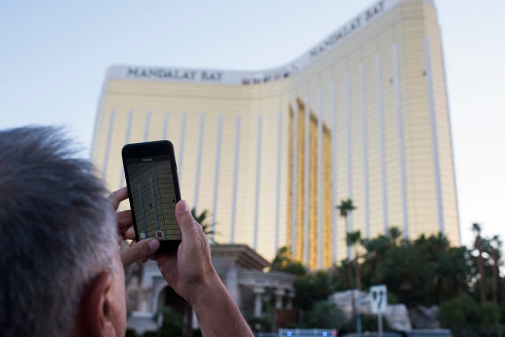 A man on the Las Vegas Strip on Oct. 4, 2017, films on his phone the two broken windows in the Mandalay Bay hotel from which killer Stephen Paddock let loose the worst mass shooting in modern American history on Oct. 1, 2017 at a country music festival across the street in Las Vegas. (Robyn Beck/AFP/Getty Images)