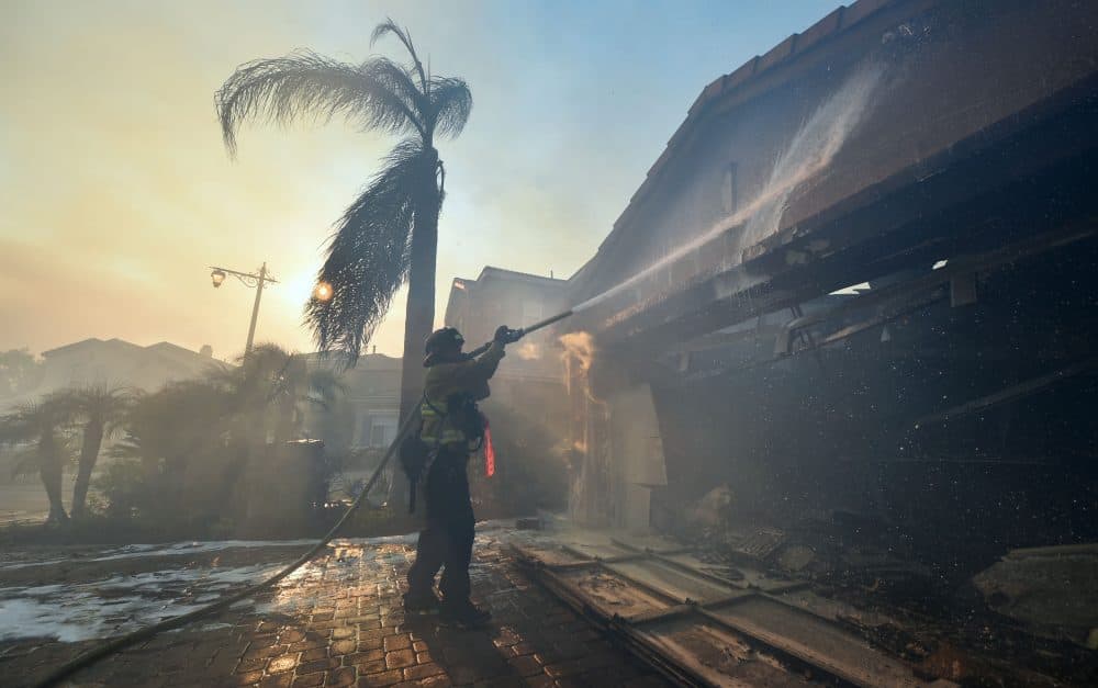 A fireman puts out a fire at a home in the Anaheim Hills neighborhood in Anaheim, Calif., on Oct. 9, 2017, after a fire spread quickly through the area destroying homes, prompting mandatory evacuations and freeway closures. (Frederic J. Brown/AFP/Getty Images)