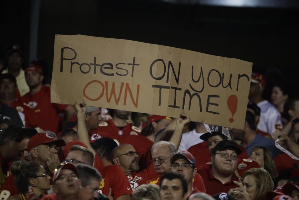 A Kansas City Chiefs fan holds a sign against the anthem protests during the first half of an NFL football game against the Washington Redskins in Kansas City, Mo., Monday, Oct. 2, 2017. (Charlie Riedel/AP)