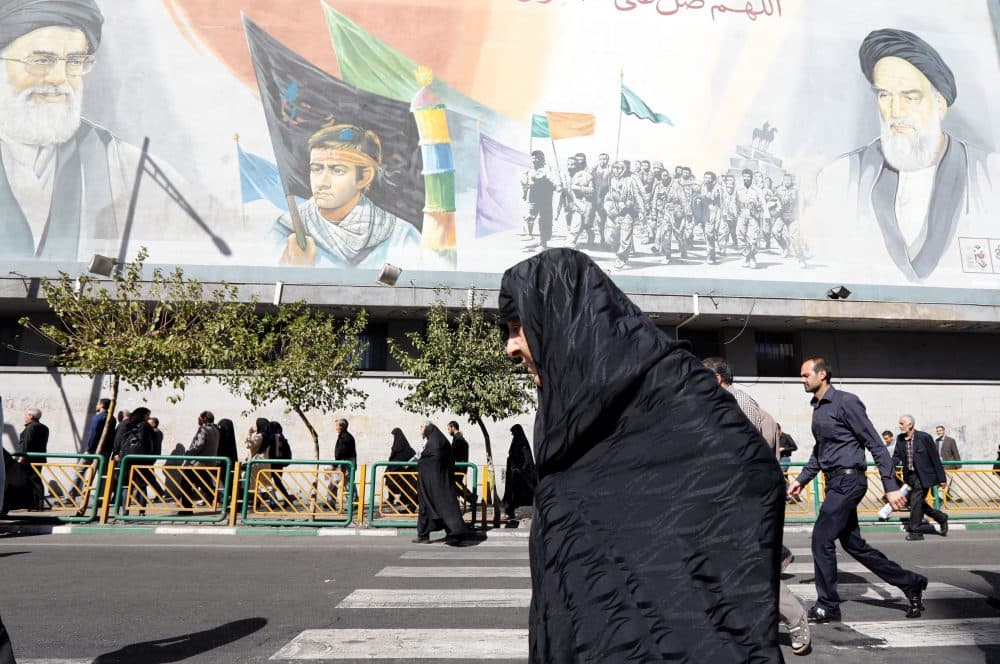 An Iranian woman walks past pictures of Iranian supreme leader Ayatollah Ali Khamenei and of late Iranian supreme leader Ayatollah Ruhollah Khomeini, following the weekly Friday prayer in Tehran on Oct. 13, 2017. (STR/AFP/Getty Images)