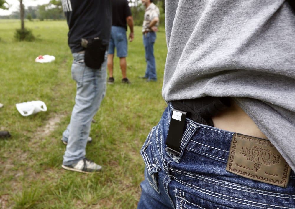 In this April 2016 photo, Crestview Baptist Church member Courtney Davis shows where she holsters her concealed firearm while another participant uses a hip holster as they await their turn to shoot during the live fire portion of a enhanced concealed carry class in Petal, Miss. (Rogelio V. Solis/AP)