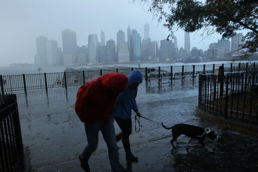 A couple walks in the rain as a darkened Manhattan is viewed after much of the city lost electricity due to the affects of Hurricane Sandy on Oct. 30, 2012 in New York. (Spencer Platt/Getty Images)