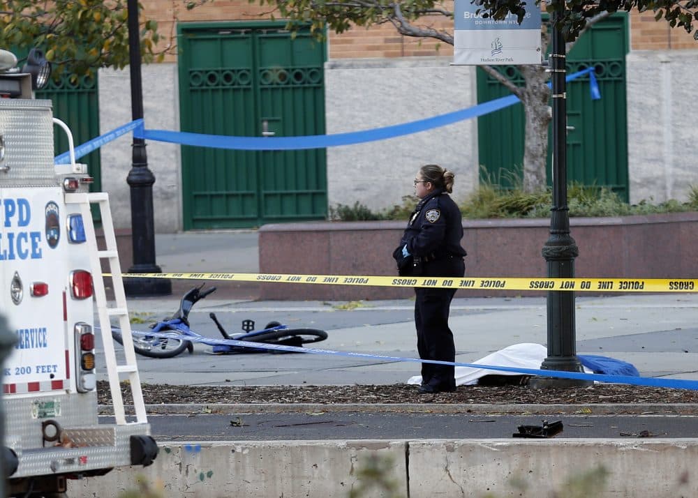 A New York Police Department officer stands next to a body covered under a white sheet near a mangled bike along a bike path Tuesday Oct. 31, 2017, in New York. (Bebeto Matthews/AP)