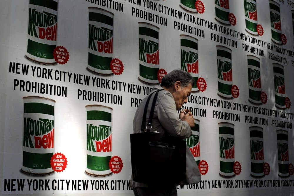A man lights a cigarette as he walks past an advertisement created in collaboration with Mountain Dew and New York Art Department, Thursday, Sept. 13, 2012, on 13th Street in New York. (Jeffrey Furticella/AP)