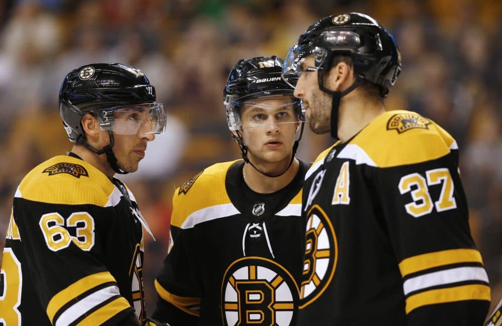 Boston Bruins' Patrice Bergeron (37) talks with line mates Brad Marchand (63) and Anders Bjork during the third period of the Bruins 4-2 win over the Chicago Blackhawks in an NHL preseason hockey game in Boston, Monday, Sept. 25, 2017. (AP Photo/Winslow Townson)
