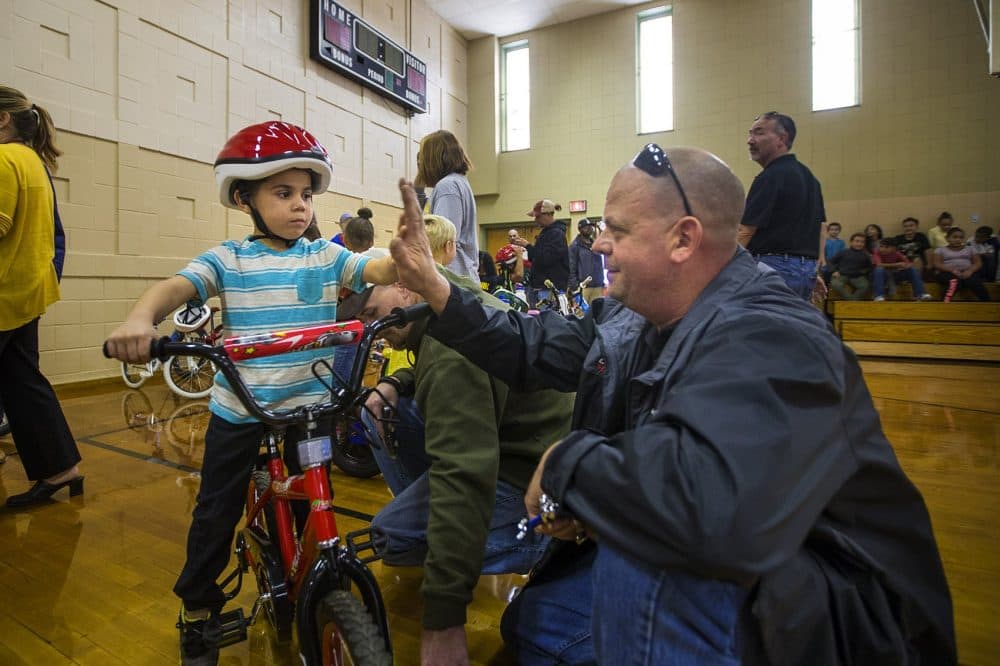 Five-year-old Christopher and Bob Charland celebrate with a high five after all the necessary adjustments have been made to his new bike so he can ride it. (Jesse Costa/WBUR)