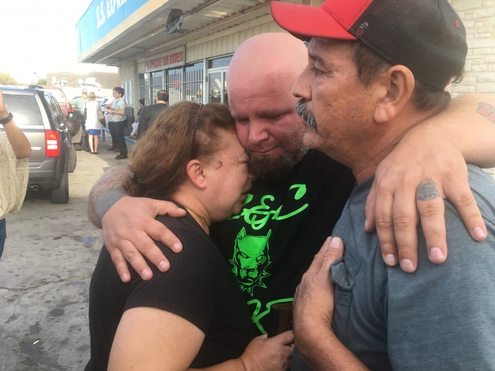 Lorenzo Flores and Terri Smith are comforted by a friend. Flores and Smith learned their friend Joann Ward and two of her children were killed in the shooting. (Joey Palacios/Texas Public Radio)