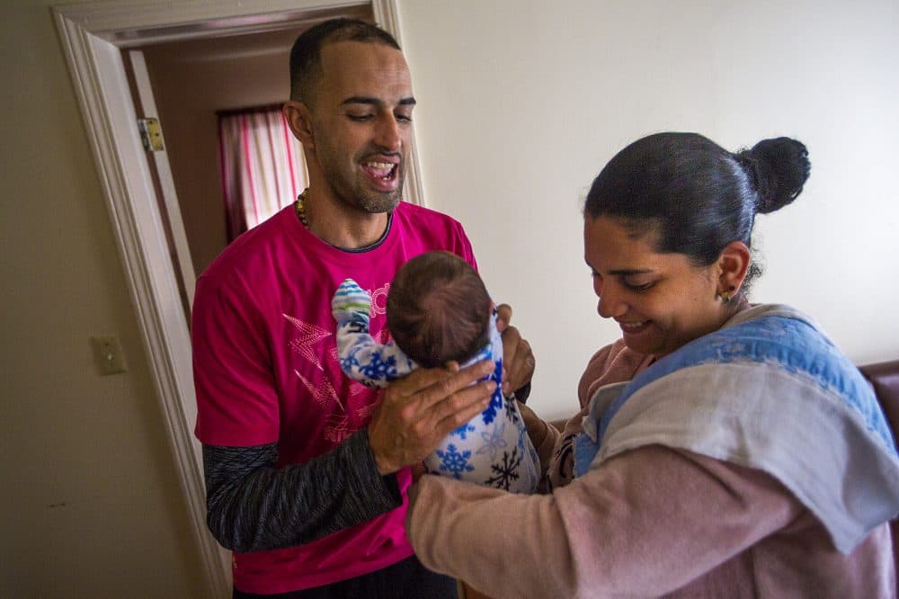 Solimari Alicea hands baby Yedriel to German Santini to hold. (Jesse Costa/WBUR)