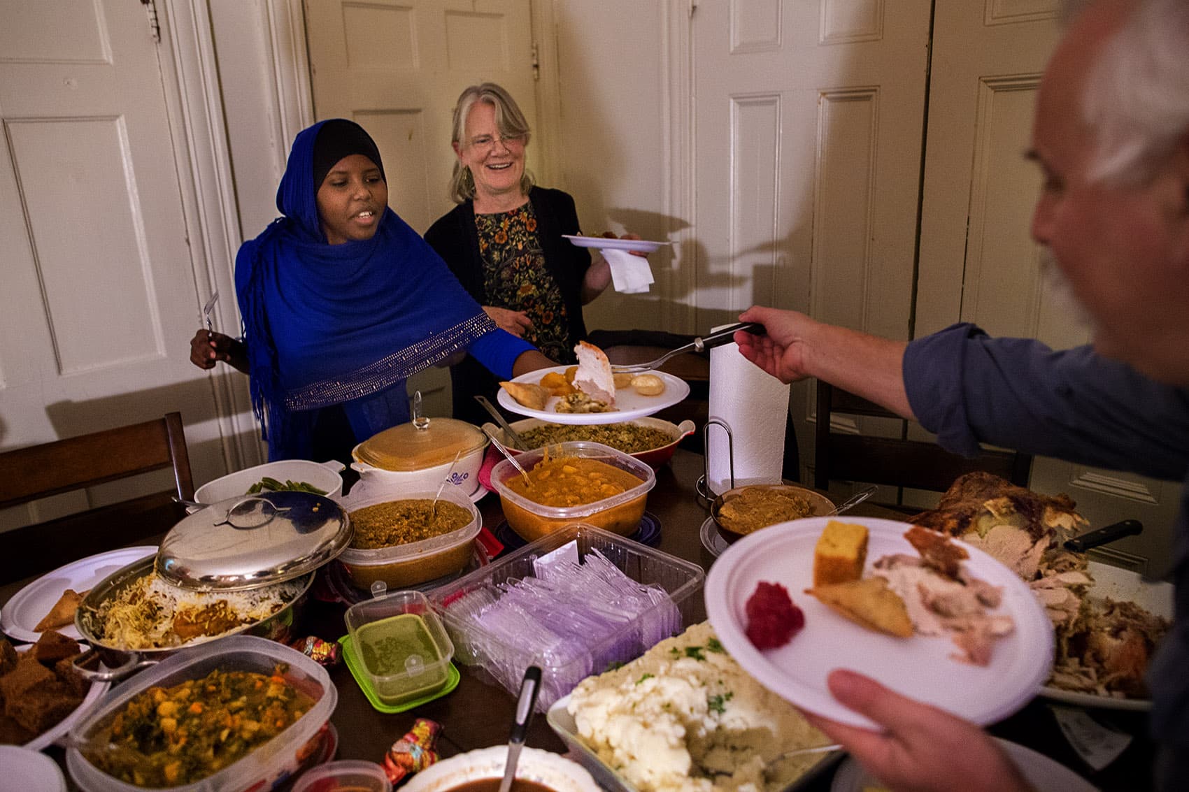 Dan Chernoff serves Asha Ahmed her very first slice of Thanksgiving turkey. Refugees from Somalia, this is the Ahmed family's first Thanksgiving in the United States. (Jesse Costa/WBUR)