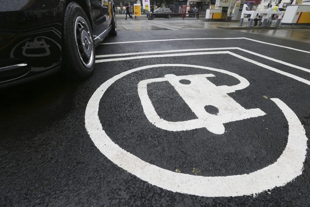 The electric vehicle recharging sign, as a new TX Cab London taxi is parked at a charging station during a media opportunity at a Shell petrol station in London on Oct. 18. (Tim Ireland/AP)