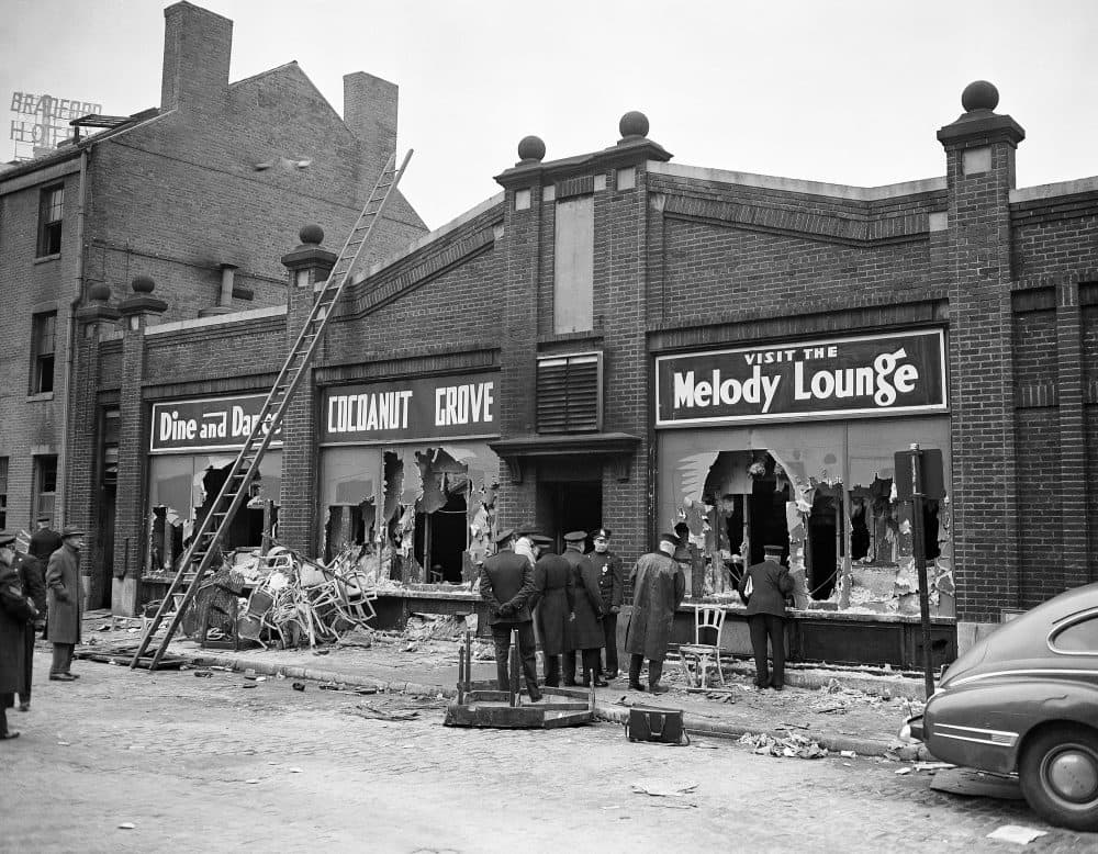 Boston police and firemen watch rear entrance to the Melody Lounge section of the Cocoanut Grove Night Club, Nov. 29, 1942. Debris from broken chairs, table and personal effects of some guests of the club when the fire broke out last night litter sidewalk and gutter. Over 400 people perished. (AP Photo)