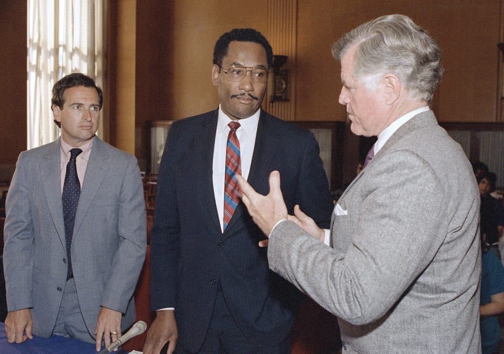 Sen. Edward M. Kennedy, D-Mass., speaks with district attorney Kevin M. Burke, left, of Essex County, Mass., and Houston Chief of police Lee Brown, center, during a hearing on drug enforcement before the Senate Judiciary Committee Tuesday, June 14, 1988 in Washington. (John Duricka/AP)