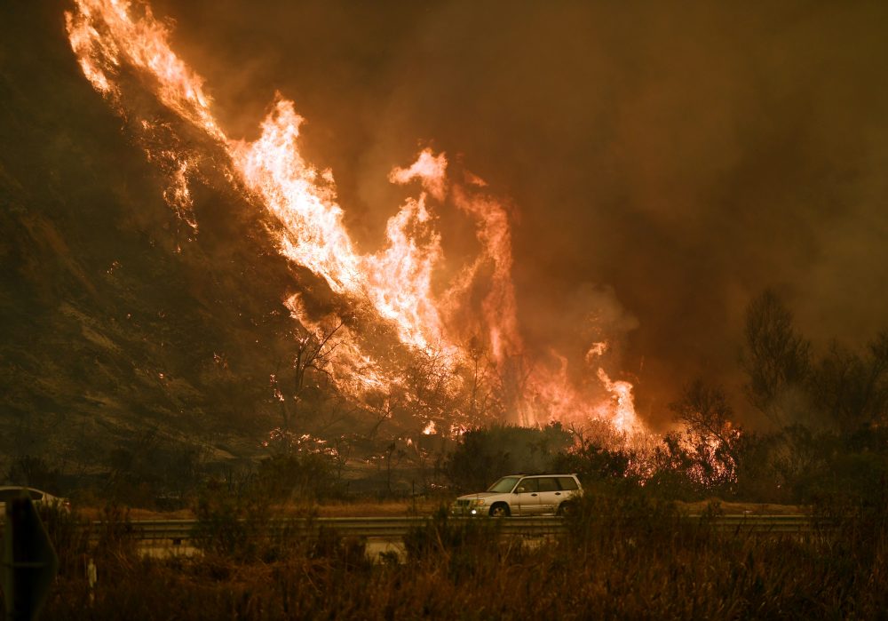 Vehicles pass beside a wall of flames on the 101 highway as it reaches the coast during the Thomas Wildfire near Ventura, Calif., on Dec. 6, 2017. (Mark Ralston/AFP/Getty Images)