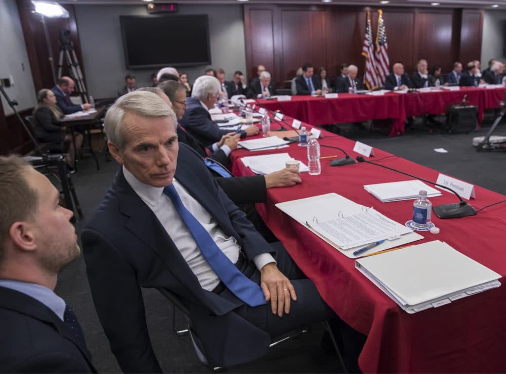 Sen. Rob Portman, R-Ohio, a member of the tax-writing Senate Finance Committee, confers with an aide as tax bill conferees gather to work on the sweeping GOP plan, on Capitol Hill in Washington, Wednesday, Dec. 13, 2017. (J. Scott Applewhite/AP)