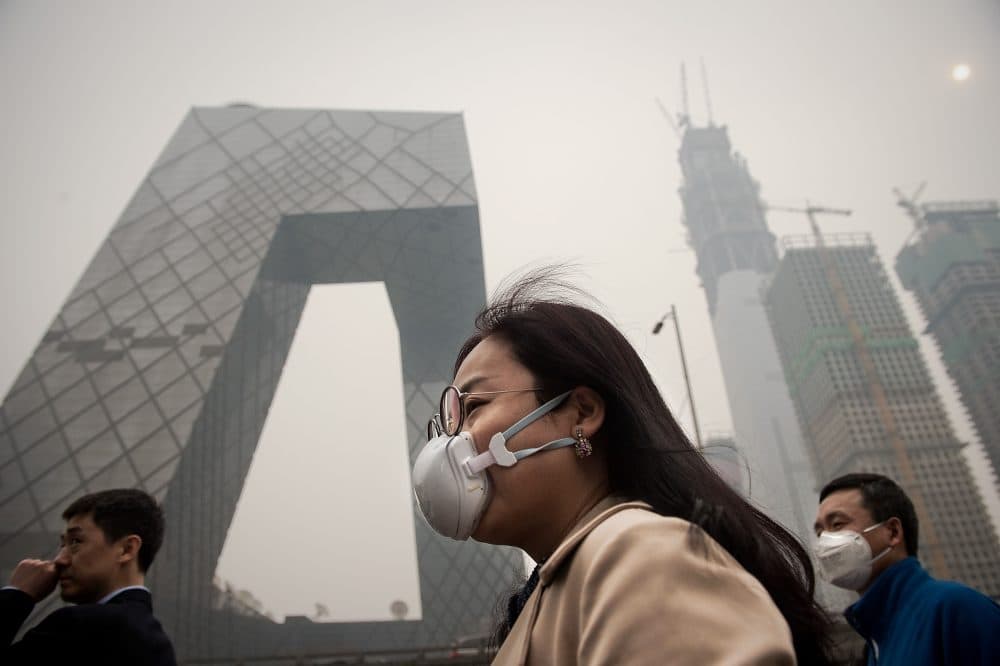 A woman wearing a protective pollution mask walks on a street in Beijing on March 20, 2017. (Nicolas Asfouri/AFP/Getty Images)