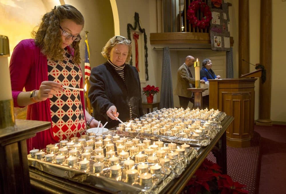 Elizabeth Hadley, left, and Lisa Barbin light candles at the 28th annual Interfaith Homeless Memorial Service to remember homeless people who died on the streets of Boston in 2017. (Robin Lubbock/WBUR)