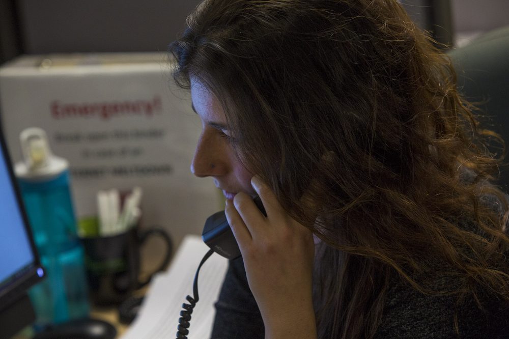 Samaritans volunteers typically answer calls and texts in a call center. They are currently working from home because of the pandemic. Here, a Samaritans volunteer, Emma, is pictured speaking with a caller in 2017. (Jesse Costa/WBUR)