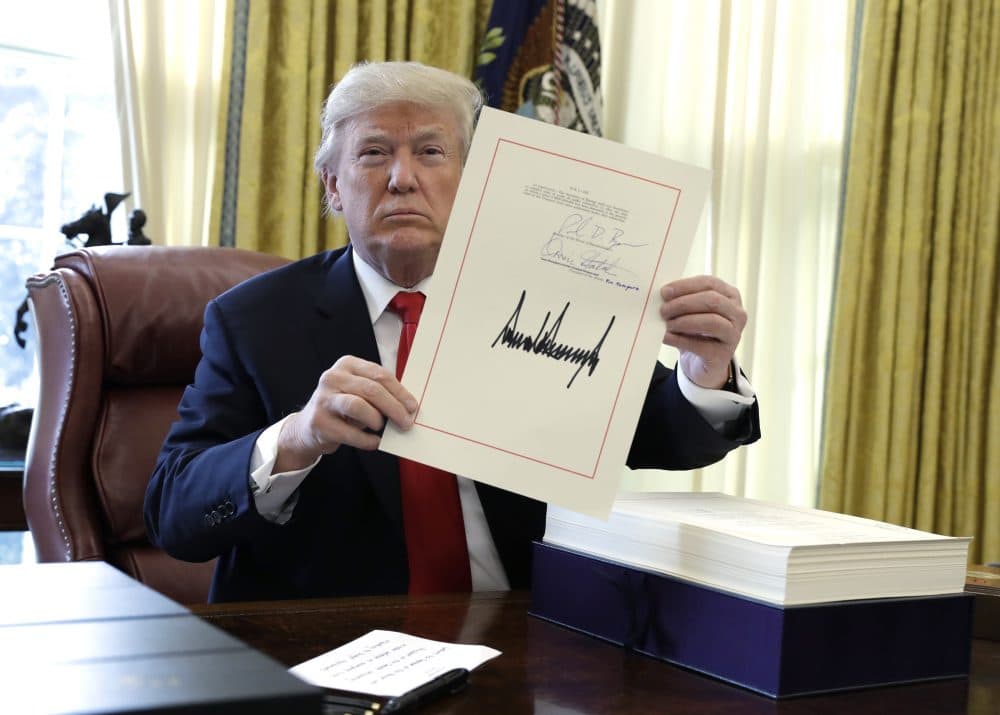 President Trump displays the $1.5 trillion tax overhaul package he had just signed, Friday, Dec. 22, 2017, in the Oval Office of the White House in Washington. Trump touted the size of the tax cut, declaring to reporters in the Oval Office before he signed it Friday that &quot;the numbers will speak.&quot; (Evan Vucci/AP)