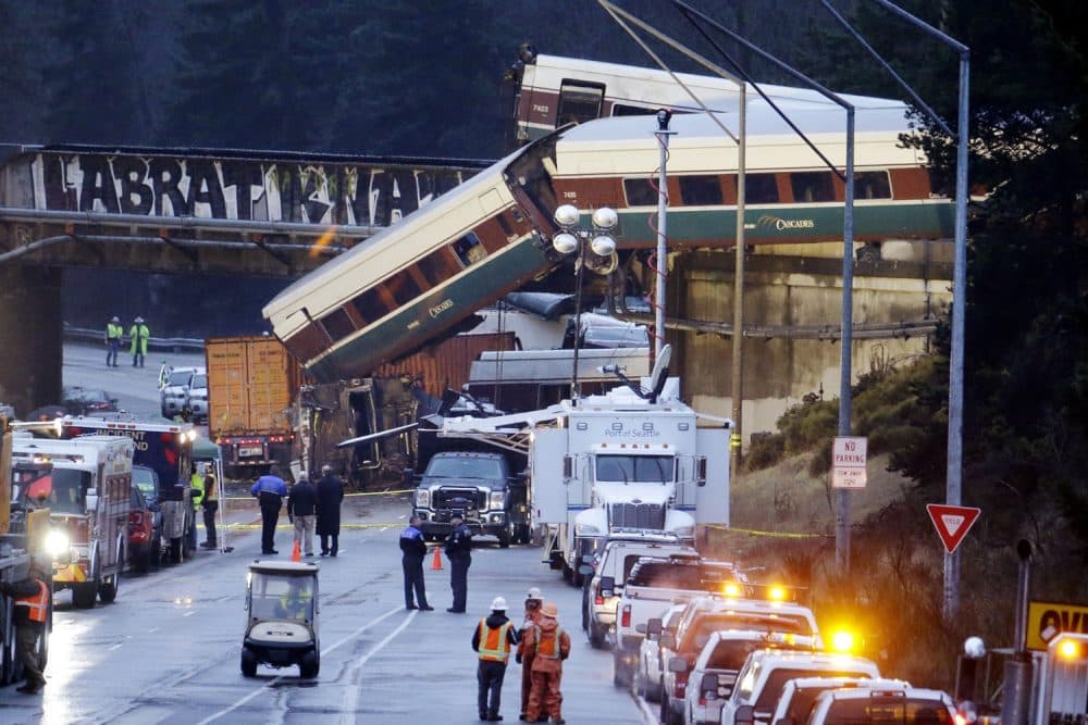Lights illuminate cars from an Amtrak train that derailed above Interstate 5, Monday, Dec. 18, 2017, in DuPont, Wash. The Amtrak train making the first-ever run along a faster new route hurtled off the overpass Monday near Tacoma and spilled some of its cars onto the highway below, killing several people, authorities said. (AP Photo/Elaine Thompson)