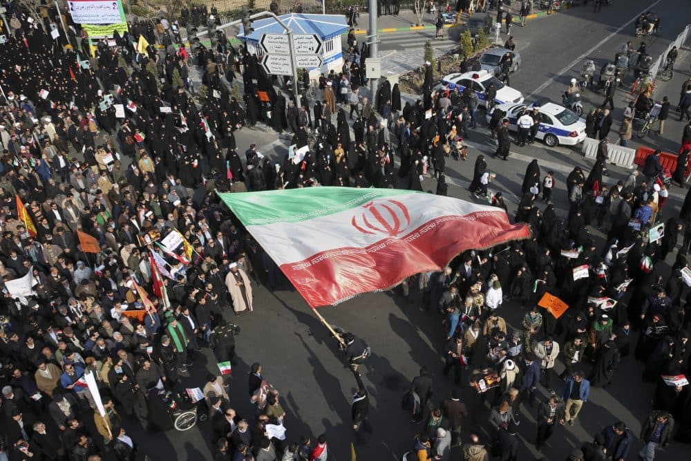 In this photo provided by Tasnim News Agency, a demonstrator waves a huge Iranian flag during a pro-government rally in the northeastern city of Mashhad, Iran, Thursday, Jan. 4, 2018. The strength of protests shaking Iran was unclear on Thursday after a week of unrest that killed at least 21 people, with fewer reports of demonstrations as government supporters again took to the streets in several cities and towns. (Nima Najafzadeh/Tasnim News Agency via AP)