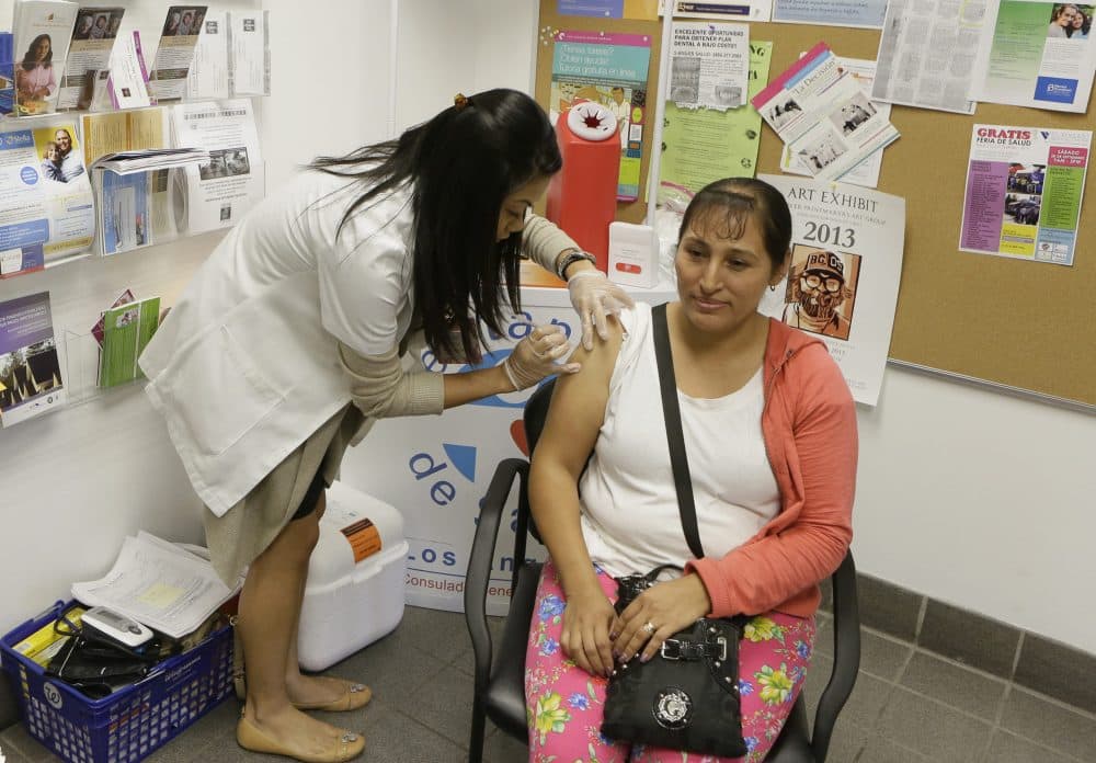 In this Oct. 1, 2013, file photo, Walgreens' pharmacist, Jennifer de Jesus, left, administers a free influenza vaccine to Ana Navarro, 33, during the Binational Health Week event held at the Mexican Consulate in Los Angeles. The flu has hit California so hard this year, pharmacies have run out of medicine to treat it, emergency rooms are packed and the death toll is rising. The Los Angeles Times reports that 27 people younger than 65 have died of the influenza in California since October. (Damian Dovarganes/AP)