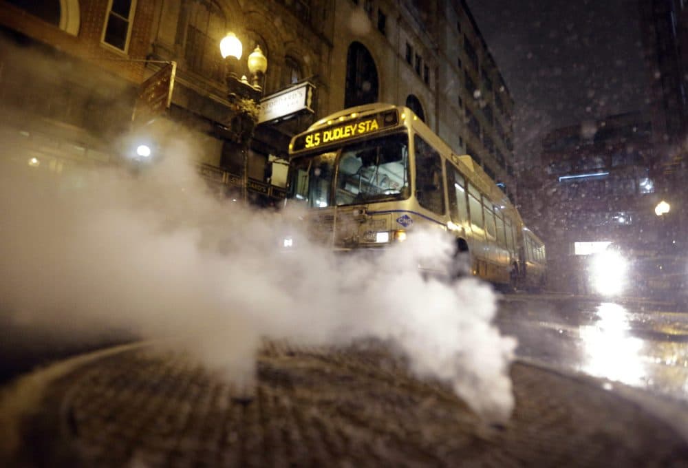 With a bus in the background, steam pours from a manhole cover in January 2015 in Boston. (Steven Senne/AP)