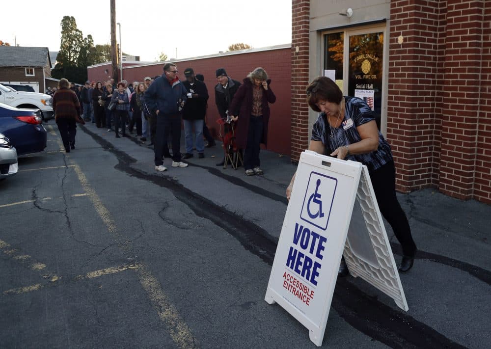 An election official places a sign as voters line up outside a polling place at the Fogelsville Volunteer Fire Co., Tuesday, Nov. 8, 2016, in Fogelsville, Pa. (Matt Slocum/AP)
