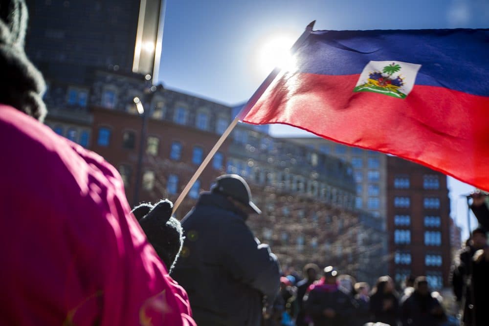 A woman waves a Haitian flag during a rally Friday at Boston City Hall denouncing the Trump administration's decision to cancel the Temporary Protected Status program for Haitians and President Trump's alleged insulting remarks about Haiti. (Jesse Costa/WBUR)