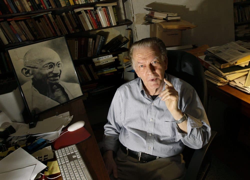 Gene Sharp poses with a photo of Gandhi, left, at his office in Boston in 2009. (Elise Amendola/AP)