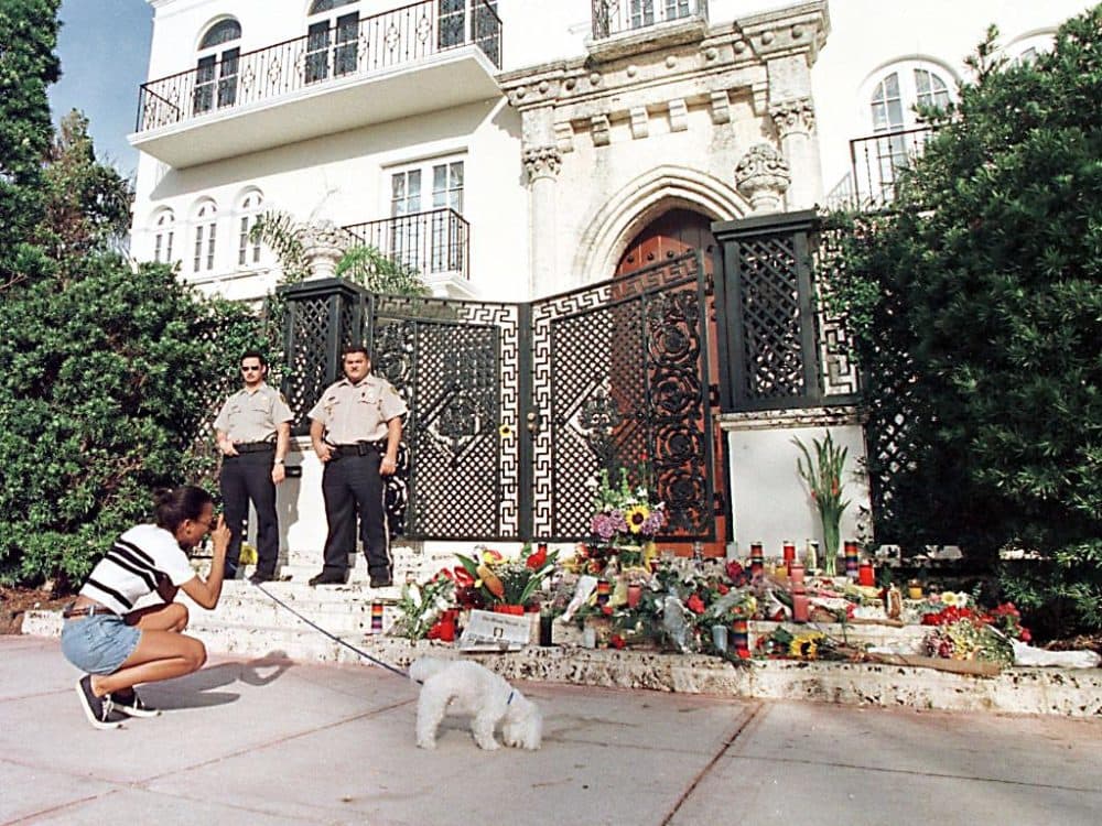 Private security guards stand in front of the house owned by Italian designer Gianni Versace on July 16, 1997, in Miami Beach, Fla., as a woman walking her dog stops to take a picture of the spot Versace was killed. (Roberto Schmidt/AFP/Getty Images)