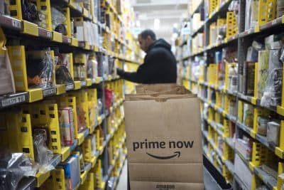 In this 2017 file photo, a clerk reaches to a shelf to pick an item for a customer order at the Amazon Prime warehouse, in New York. (Mark Lennihan/AP)