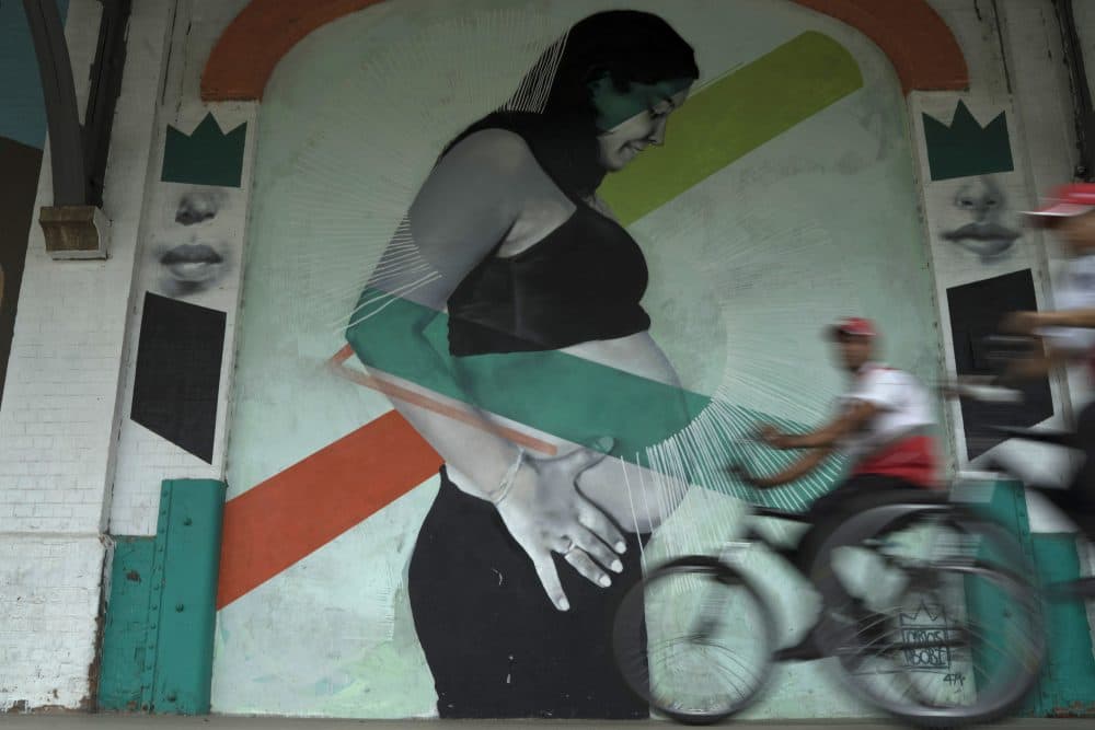 In this Wednesday, Jan. 3, 2018 photo, police officers drive their bicycles past a mural art by Brazilian artist Carlos Bobi in Rio de Janeiro, Brazil. As in many countries, abortion is a subject of taboo in Brazil, a socially conservative nation with the world's largest Roman Catholic population as well as a growing evangelical Christian community. (Leo Correa/AP)