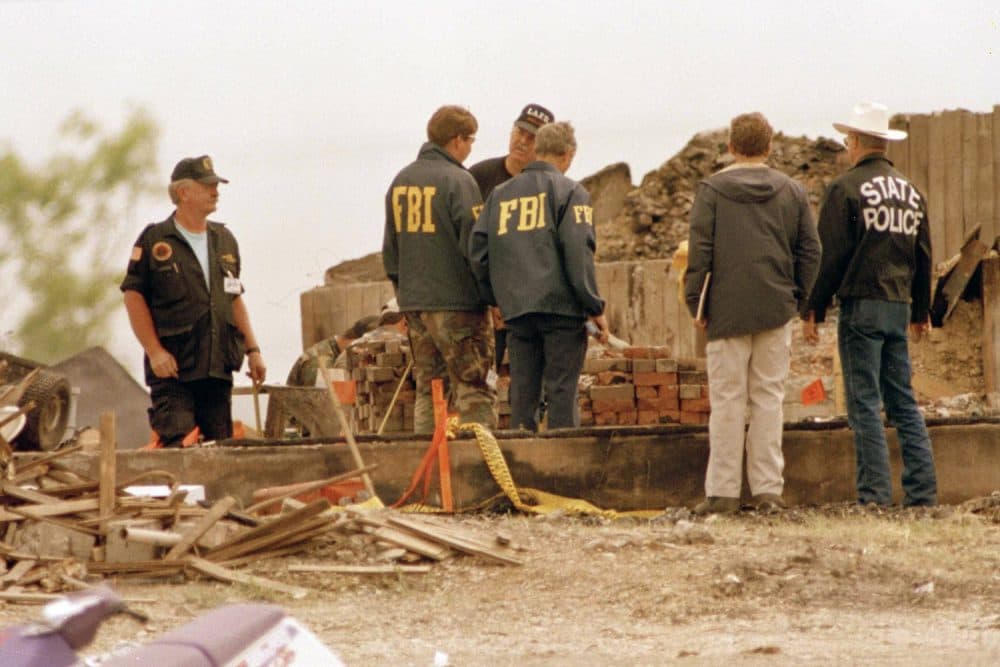 FBI agents, center, confer with another investigator, facing camera, who wears a Los Angeles Fire Department cap, at the site of the destroyed Branch Davidian compound near Waco, April 27, 1993. Lawyers for some of the Branch Davidians questioned the impartiality of an outside team of investigators that concluded the cultists themselves set the fire that destroyed the compound. (AP Photo/Ron Heflin)