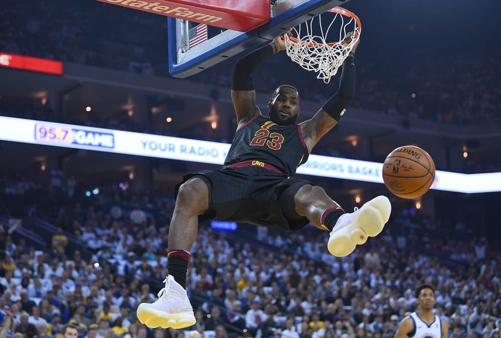 LeBron James of the Cleveland Cavaliers hangs onto the rim after a slam dunk against the Golden State Warriors during an NBA basketball game at Oracle Arena on Dec. 25, 2017 in Oakland, Calif. (Thearon W. Henderson/Getty Images)