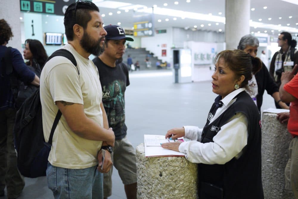 Gustavo Lavariega, a volunteer with Deportees United, talks with an official from Mexico's labor department as he waits for deportees to arrive on a flight from Texas. (Liz Jones/KUOW)
