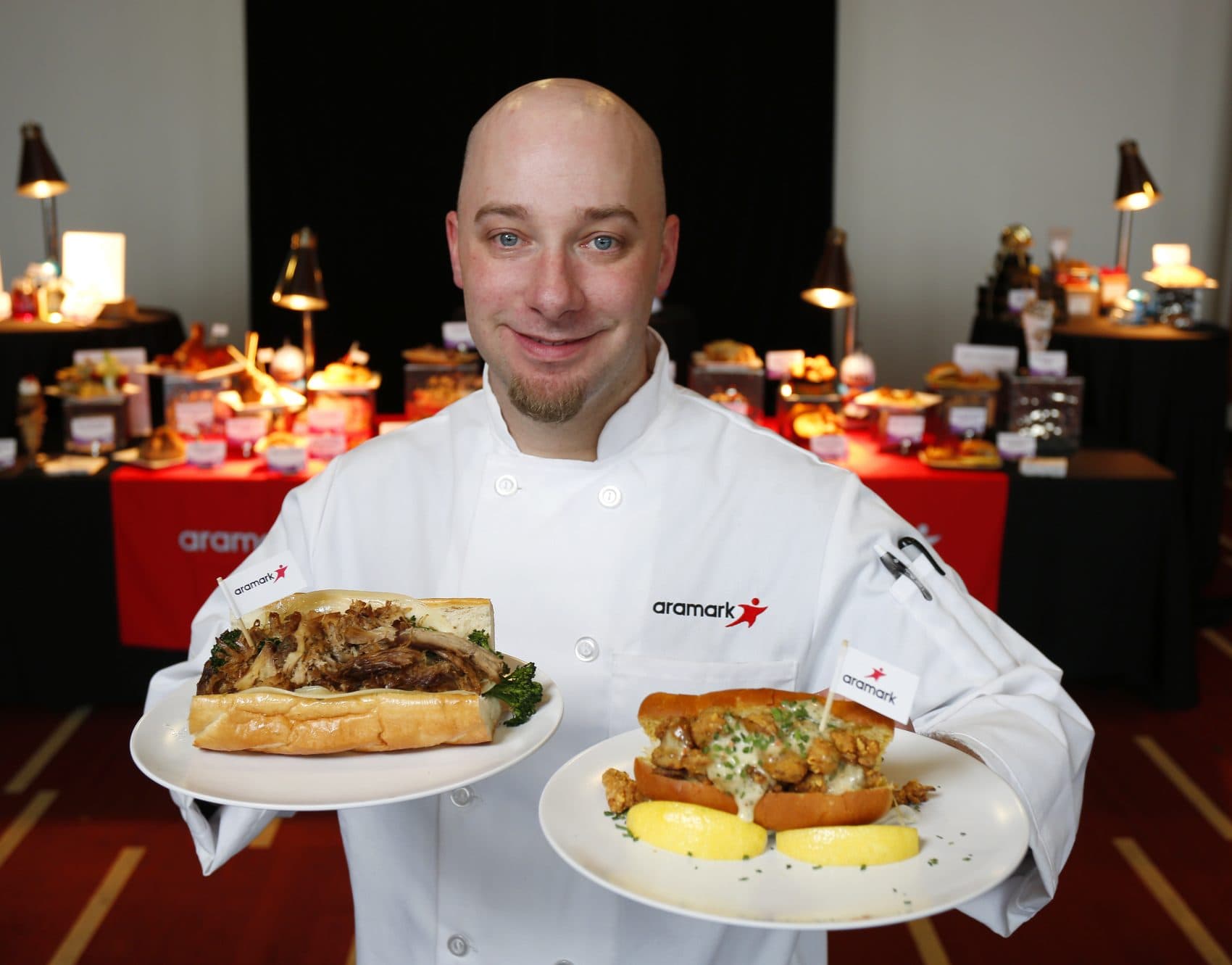 Aramark Senior Executive at U.S. Bank Stadium Chef James Mehne holds signature sandwiches he created for Super Bowl LII celebrating hometown flavors of the Philadelphia Eagles, left, and New England Patriots, right, at the Super Bowl menu preview in Minneapolis. (Andy Clayton-King/AP for Aramark)