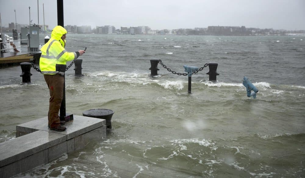 A man takes photographs as floodwaters surge at Boston's Long Wharf. (Robin Lubbock/WBUR)