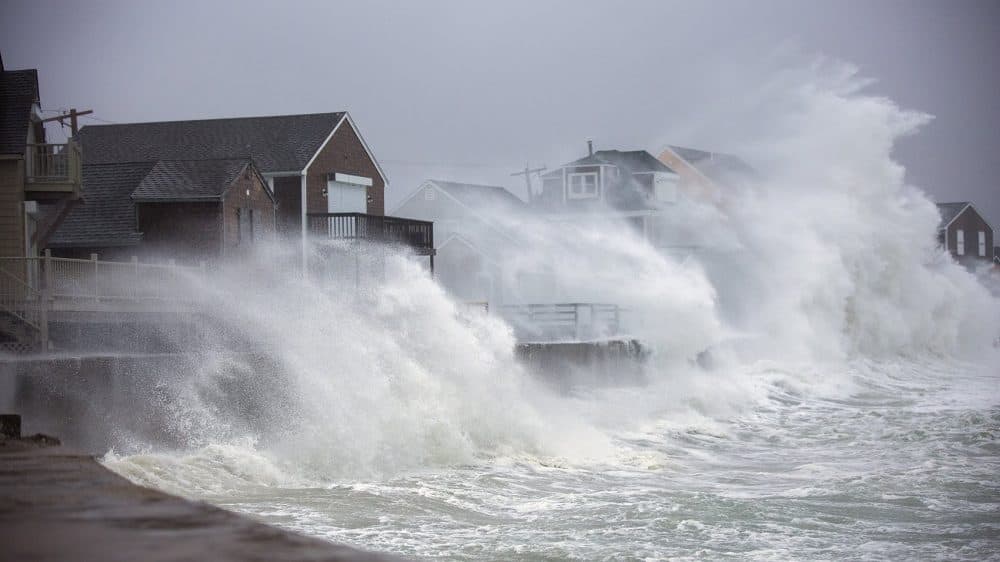 Houses along Lighthouse Road in Scituate are engulfed by waves crashing off the seawall. (Jesse Costa/WBUR)