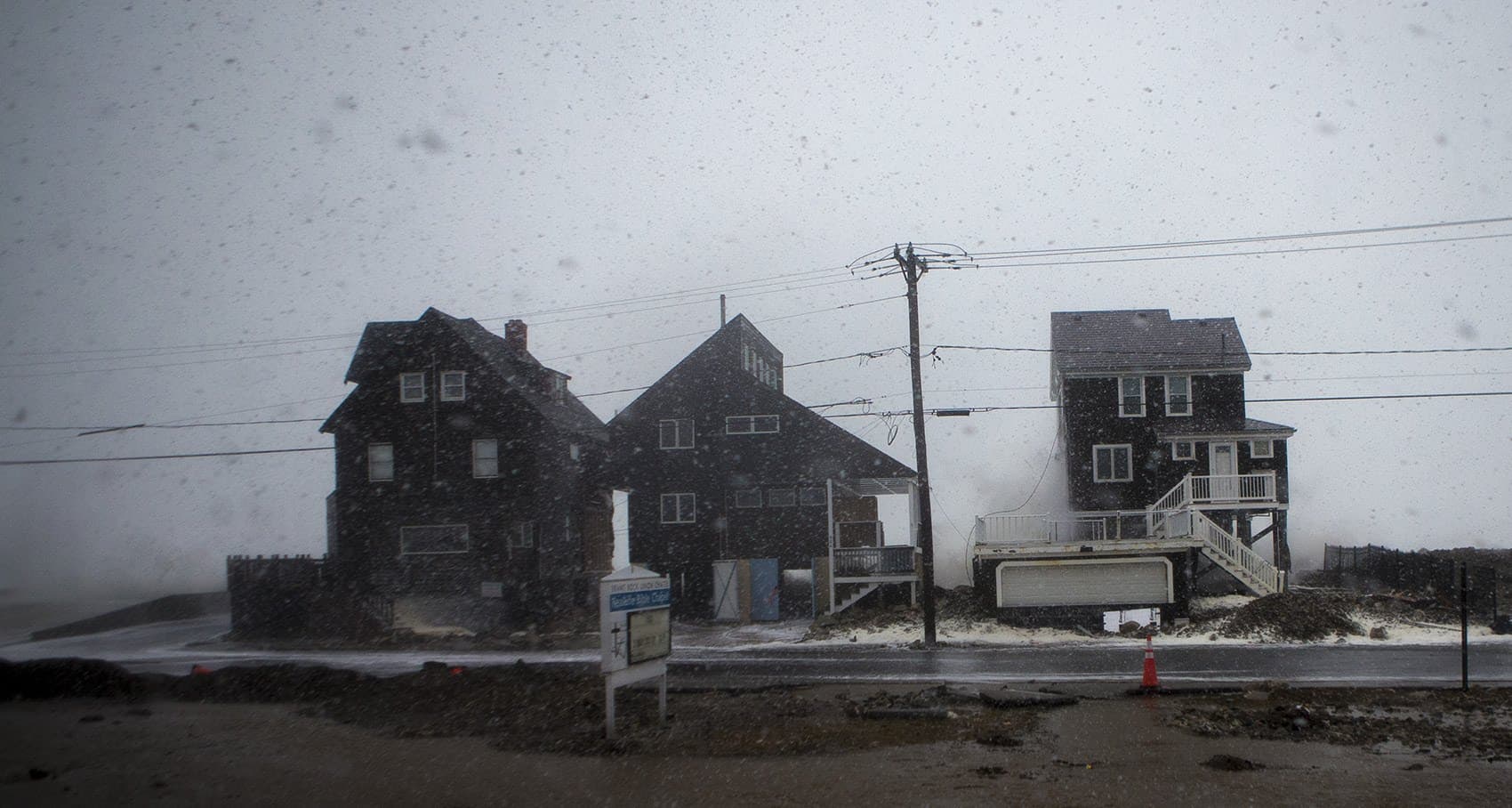 Waves crash along the seawall and houses on Ocean Street in Marshfield at high tide. (Jesse Costa/WBUR)