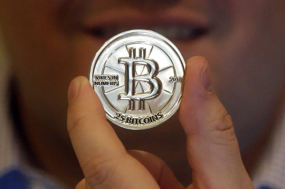 In this 2013 file photo, Mike Caldwell holds a 25 Bitcoin token at his shop in Sandy, Utah. (Rick Bowmer/AP)