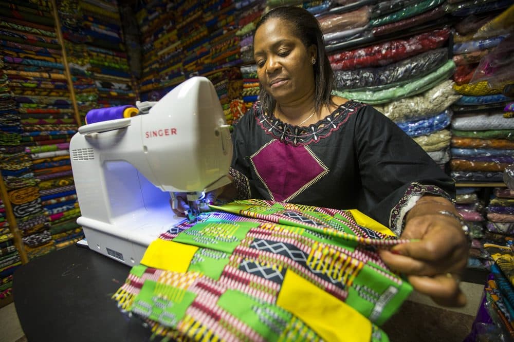 Ebby Ihionu works on a pleated dance skirt at Elegance African Fashions in Dorchester. (Jesse Costa/WBUR)