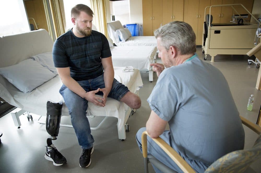Brandon Korona, an Army veteran whose left leg was injured in an IED explosion in Afghanistan, talks with Dr. Matthew Carty at Brigham and Women’s Faulkner Hospital in Boston. (Robin Lubbock/WBUR)