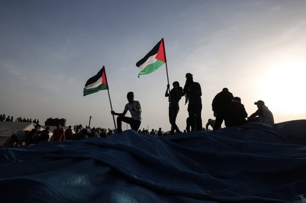 A Palestinian protester waves his national flag at the site of a tent protest, near the border with Israel, east of Khan Yunis, in the southern Gaza Strip on April 4, 2018. (Said Khatib/AFP/Getty Images)