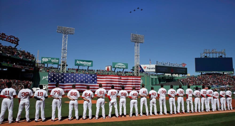 Boston Red Sox players line up along the first base line as four F-16's, from the Air National Guard's 134th Fighter Squadron in Burlington, Vermont, fly over during ceremonies prior to a home opener. (Charles Krupa/AP)