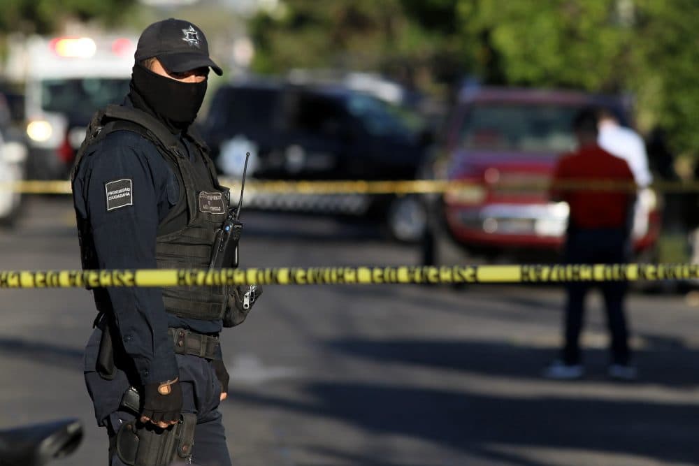 A police officer stands guard as state prosecutors inspect a pickup truck found abandoned with the bodies of six men, some of them decapitated, which are thought to have been killed by alleged traffickers of a rival cartel, in the Morelos neighborhood in Guadalajara, Mexico, on March 6, 2018. Mexico has suffered a wave of violence linked to drug trafficking that has intensified in recent years. (Ulises Ruiz/AFP/Getty Images)