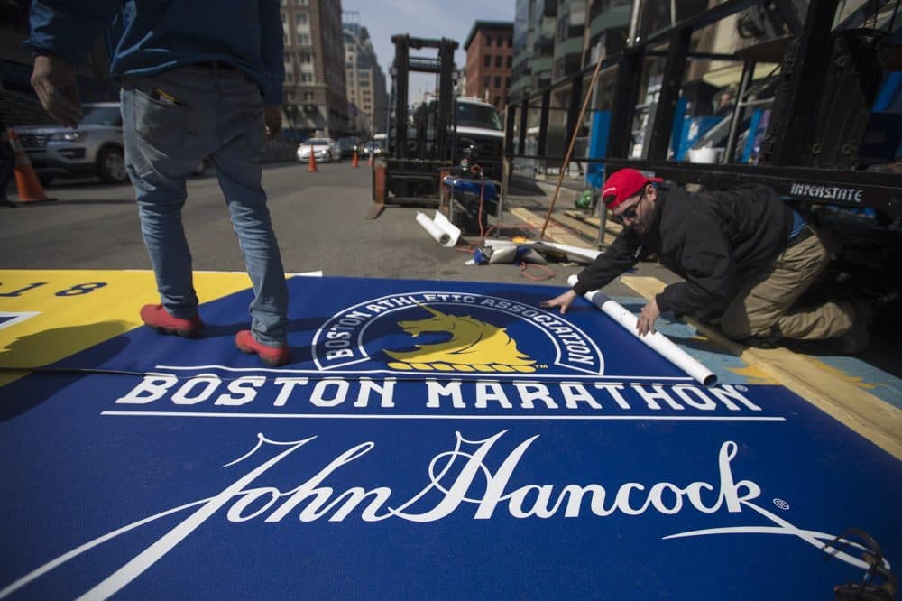 Workers lay down the new finish line for the 2108 Boston Marathon. (Jesse Costa/WBUR)